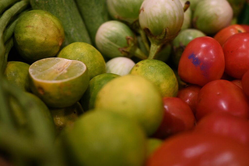 DZ3 0616 Fresh Thai produce limes round eggplants and cherry tomatoes piled together at a local market in Sattahip