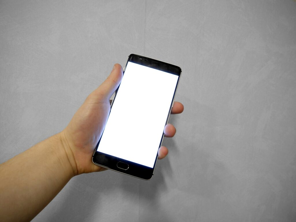 Hand holding smartphone with blank white screen